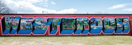 A colorful mural in Westbrook spells out WESTBROOK, with each letter filled with detailed scenes of local landscapes, buildings, overdose prevention efforts, and community life, set against a blue sky and grassy foreground.