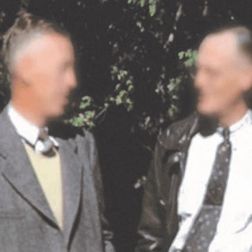 Two men stand outdoors in front of leafy trees, dressed in suits and ties. Their faces are blurred, and the lighting suggests it is daytime, perhaps after attending an Alcoholics Anonymous support group.