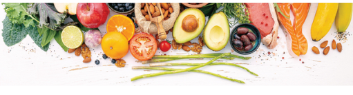 Colorful fruits, vegetables, nuts, and whole grain bread arranged on white surface from above.