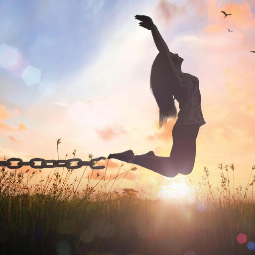 Silhouette of person jumping with broken chain in a field at sunset.