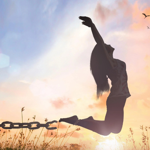 Silhouetted figure with arm raised breaking free from chain at sunset with tall grass.