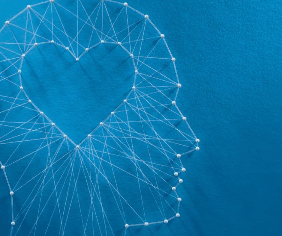 A heart outline formed from white pins and threads on a deep blue background.