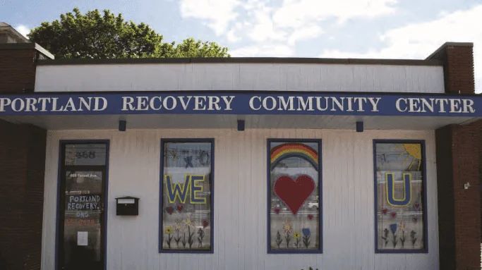 The exterior of the Portland Recovery Community Center, its windows painted with rainbows and lettering.