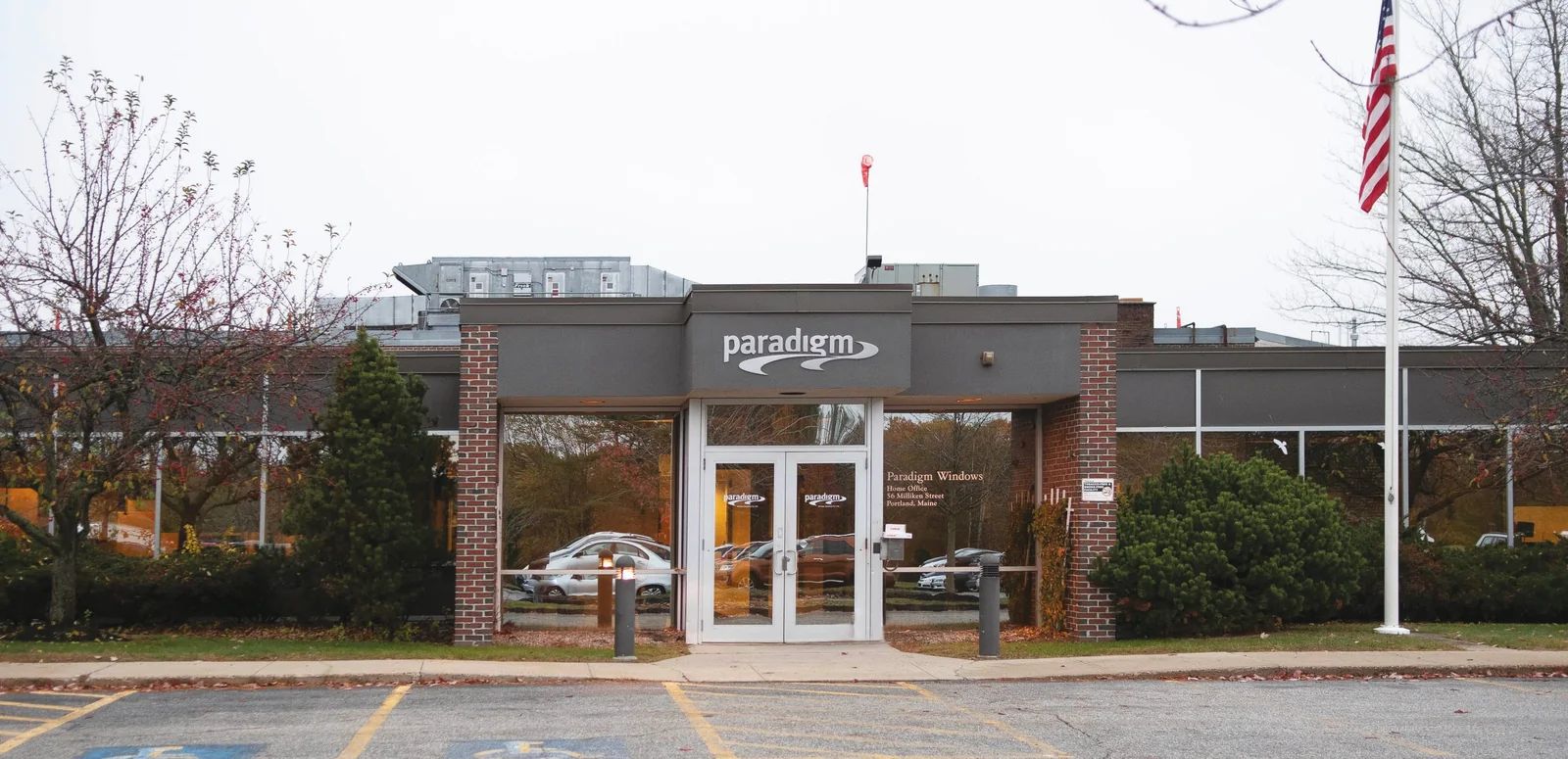 The exterior of the Paradigm Windows building and its parking lot on an overcast day.