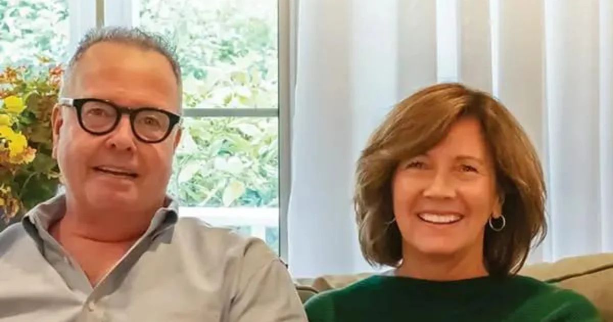 A couple sitting together on a sofa in a bright living room, both smiling.